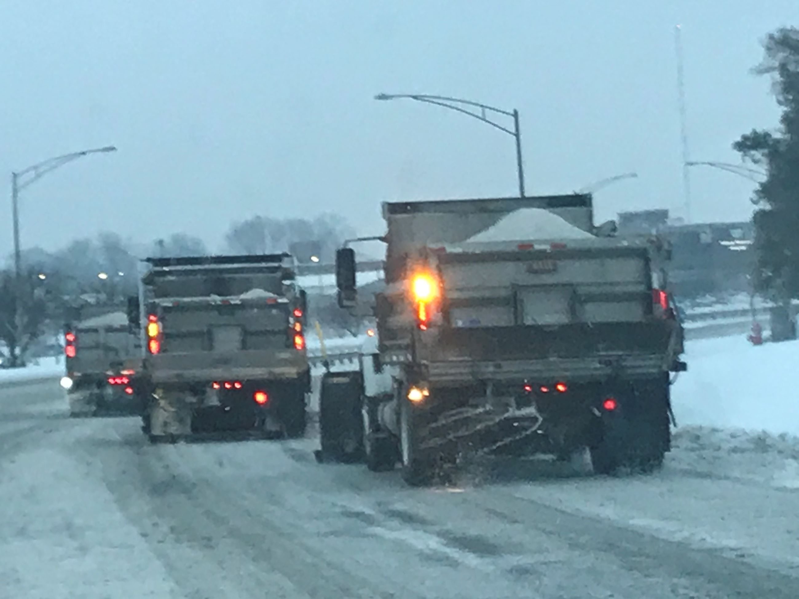 Three city snow plows plowing snow on State Route 47 during a winter storm